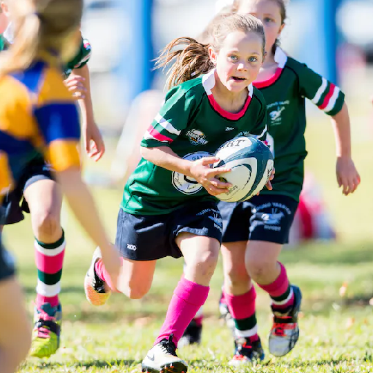 Young girl running holding rugby ball